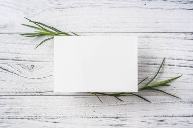 Mockup için beyaz Vintage ahşap arka planda yeşil yaprakları ile boş tebrik kartı üst görünümü