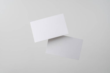 Mockup için gri arka planda havada uçan beyaz kartvizitler