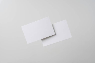 Mockup için gri arka planda havada uçan beyaz kartvizitler