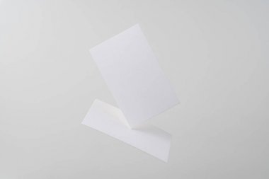 Mockup için gri arka planda havada uçan beyaz kartvizitler