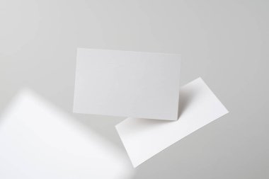 Mockup için gri arka planda havada uçan beyaz kartvizitler