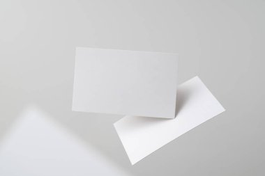 Mockup için gri arka planda havada uçan beyaz kartvizitler