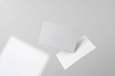 Mockup için gri arka planda havada uçan beyaz kartvizitler