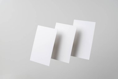 Mockup için gri arka planda havada uçan beyaz kartvizitler