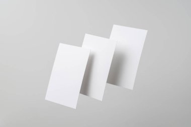 Mockup için gri arka planda havada uçan beyaz kartvizitler