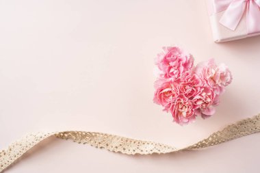 Kalp şekli ve Vintage şerit ile karanfil çiçekler, kopya alanı ile pembe arka planda hediye kutusu