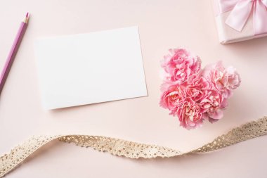 Tasarım kavramı-kalp şekli, Vintage şerit, hediye kutusu ve pembe arka planda tebrik kartı ile karanfil üst görünümü.