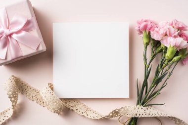 Anne gün mockup için pembe arka planda karanfil, Vintage Dantel Şerit, hediye kutusu ve tebrik kartı üst görünümü