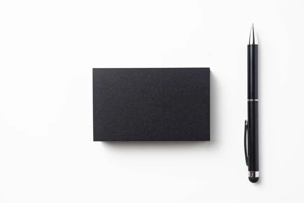 モックアップ用の白い背景に隔離されたボールペンを持つ黒い名刺のトップビュー — ストック写真