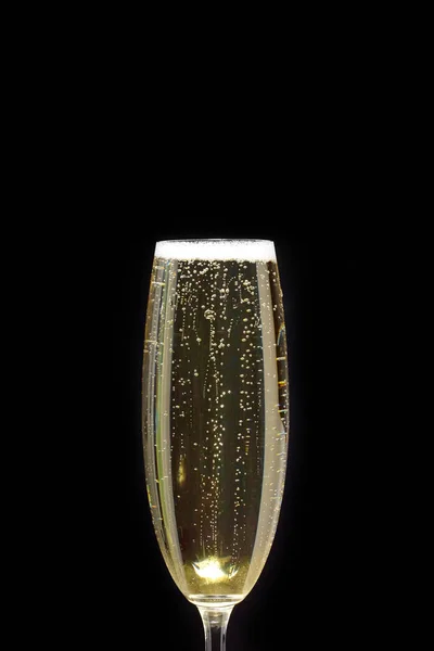 A Close-up of a champagne flute with bubbles and foam on a black background