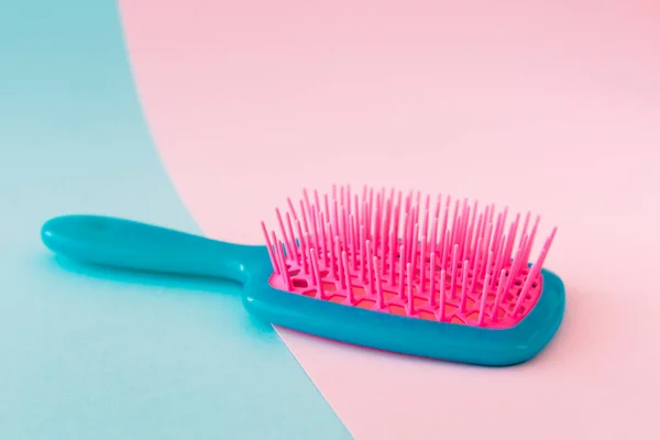 Parlak mavi ve pembe arkaplanda renkli plastik saç fırçası. Güzellik konsepti.