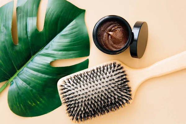 Hair care concept. Wooden hairbrush and natural hair mask lie on beige background. Spa care. Hair treatment.