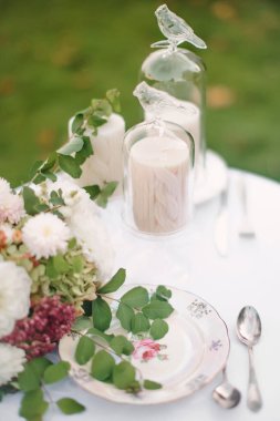 Düğün ya da doğum günü misafirleri için çiçek ve mumlarla dekoratif şenlik masasının yakın çekimi. Yumuşak odak.