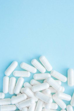 Mavi arka planda uyuşturucu bulunan beyaz kapsüller. Bir avuç dolusu hap, tedavi konsepti. Boşluğu kopyala.
