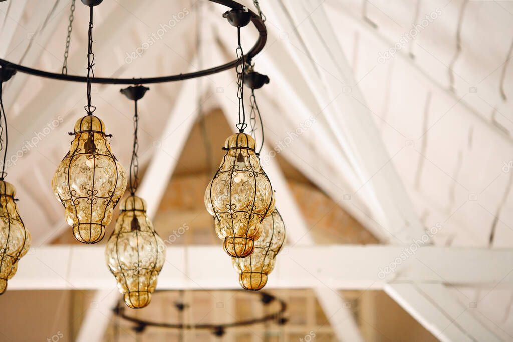 Vintage chandelier in boho style with transparent shades of yellow glass.