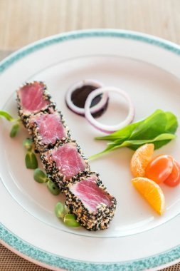 Susam beyaz plaka üzerinde yeşil salata ile kurutulmuş ton balığı