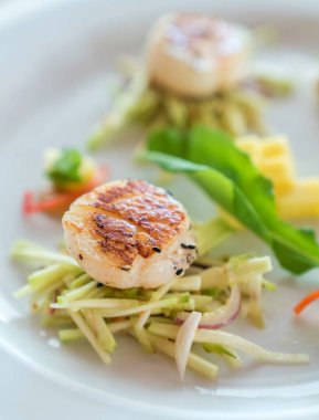 Kurutulmuş hokkaido scallopes beyaz tabakta baharatlı mango salatası ile