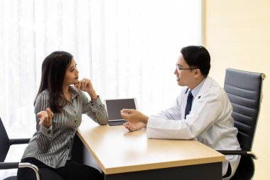 Doktor hastaya tablet kullanarak güzellik kliniğinde tedavi yöntemini açıklayan