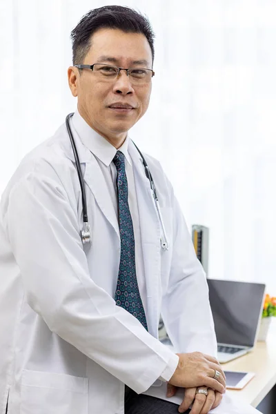 Portrait of senior Doctor in examination room medical office.