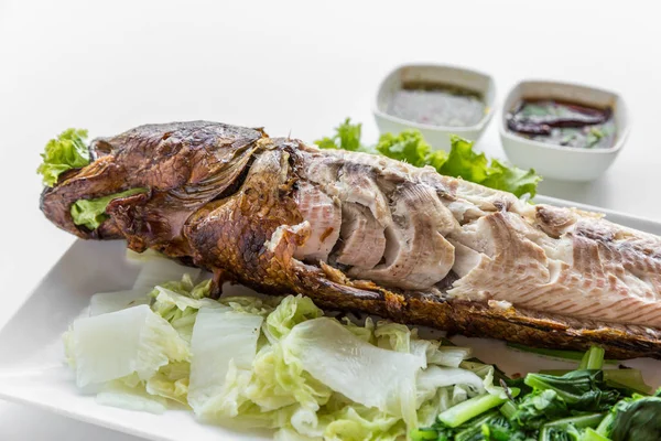Grilled fish with vegetables and sauce on white background