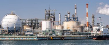 Tokyo yakınlarındaki Kawasaki City 'deki bacadan çıkan dumanla gaz depolama ve boru hattının yapısına sahip petrol petrokimya fabrikası.