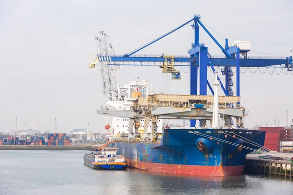 オランダのロッテルダム港で国際海上貨物輸送を待っている桟橋ドックポートに貨物スタックを持つ大きな貨物コンテナ船 — ストック写真