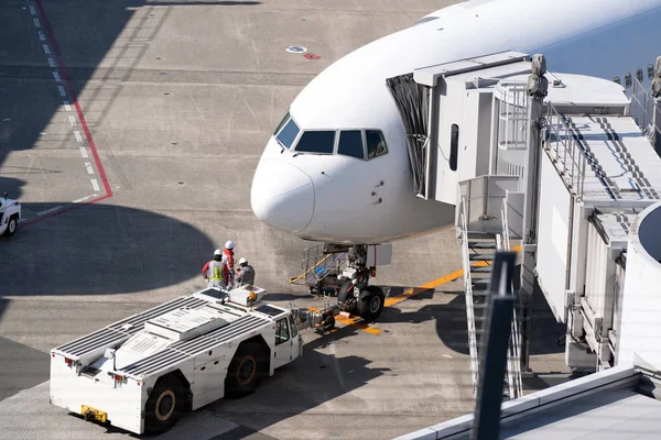 空港のジェットブリッジで白い飛行機の降ろしと乗客の積み下ろし — ストック写真