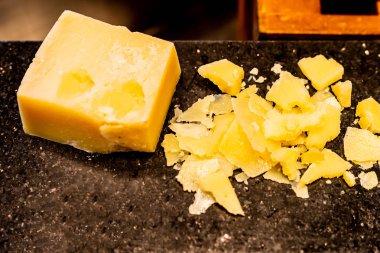 Açık büfede siyah taş tabakta parmesan peyniri.