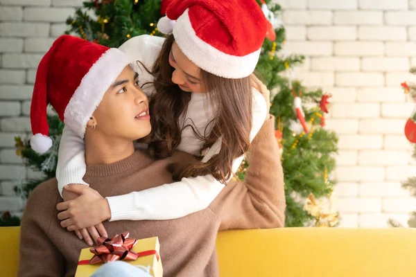 若いですアジアの大人ティーンカップル抱擁とお祝いクリスマス休暇で一緒にリビングルームでクリスマスツリー装飾 — ストック写真