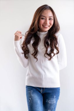 Kış için beyaz kazak giyen güzel Asyalı genç bir kızın portresi beyaz arka plandaki boş fotokopi alanını işaret ediyor.