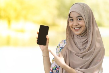 Güzel görünümlü genç, mutlu, Müslüman, Asyalı, cep telefonu tutan bir kızın portresi.