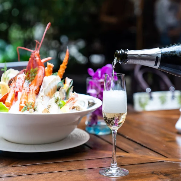 白ワインをワイングラスに注ぎ込み 氷の上に大きなボウルシーフードを背景にレストランで顧客にサービスを提供するウェイター レストランの美食食品や飲料消費主義の概念 — ストック写真