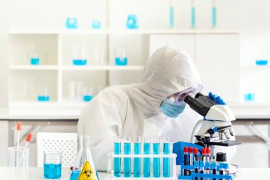 Genç Asyalı bilim adamı, 2019 ncov dünya pandemisi için Coronavirus COVID-19 aşısını incelemek üzere laboratuvarda mikroskop araştırması yapıyor. Sağlık hizmetleri kavramı.