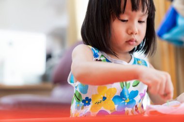Asian girl child sewing in living room at home as home schooling while city lockdown because of covid-19 pandemic across the world. Home Schooling prepare for Preschool concept. clipart