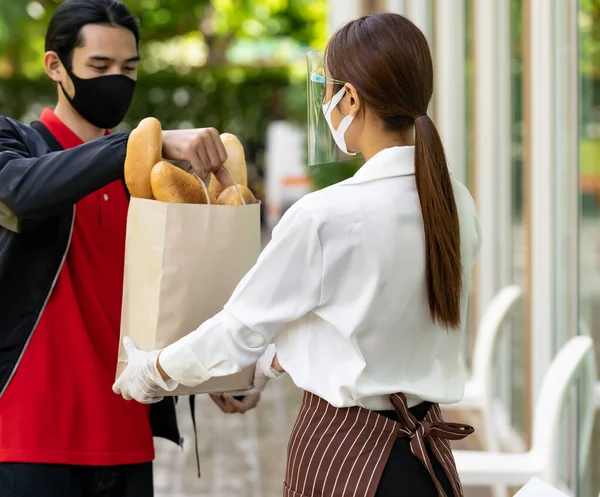 Delivery Asian bike man pick up bakery grocery bag from bakery shop to  deliver to customer who make online order. Food delivery service concept in  new normal after coronavirus pandemic. | Stock