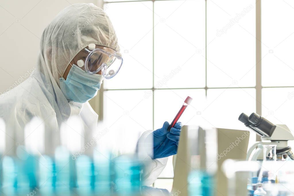 Scientists hold blood sample test tube and examine for his research and develop vaccine for coronavirus covid-19 pandemic. Medical Science technology and health care concept.