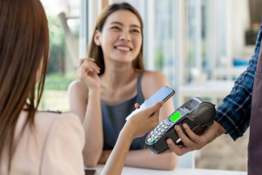 Yeni normal bir sosyal yol restoranında yemek yedikten sonra çevrimiçi cep telefonu ödemesi yapmak için Asyalı kadın moblie telefon. Çevrimiçi iletişim ve teknoloji kavramı.