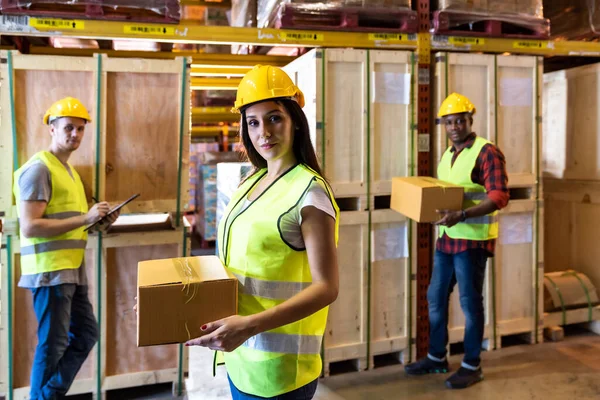 Portrait of caucasian white woman warehouse worker hold parcel box with her colleague working about stock in warehouse distribution center environment. Using in business warehouse and logistic concept