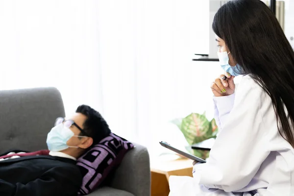 在Covid 19流感大流行后 心理治疗师女医生访问病人之家 与躺在客厅沙发扶手椅上的沮丧的亚洲商人一起工作 就心理健康问题进行咨询 — 图库照片
