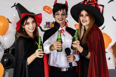 Asyalı genç yetişkinlerin portre arkadaşları Cadılar Bayramı karnavalı şenliğini kutluyor. Cadılar Bayramı kostümü giyip şarkı söyleyip tezahürat yapıyorlar. Cadılar Bayramı kutlaması ve uluslararası tatil konsepti