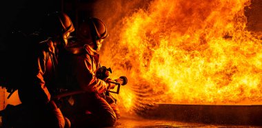 Panoramik itfaiyeciler, yangını kontrol etmek ve yayılmak için değil, petrolden çıkan alevlerle savaşmak için Twirl su sisi tipi yangın söndürücü kullanıyorlar. İtfaiyeci ve endüstriyel güvenlik kavramı.