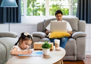 Koronavirüs covid-19 pandemisi yüzünden şehir kilitlenirken Asyalı kız evde babasıyla birlikte dizüstü bilgisayarla resim çiziyor. Evden çalışan Yeni Normal yaşam tarzı.