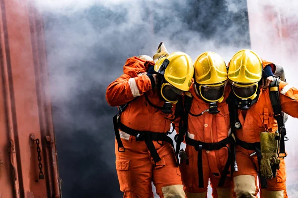 Asian firefighters rescue their team colleague from from burning building. Firefighter safety rescue from accident and public service concept.