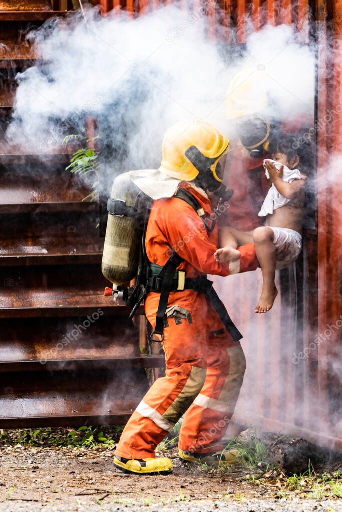 Firefighter rescue girl little child from burning building. He hold the girl and rescue her through window of building. Firefighter safety rescue from accident and public service concept.