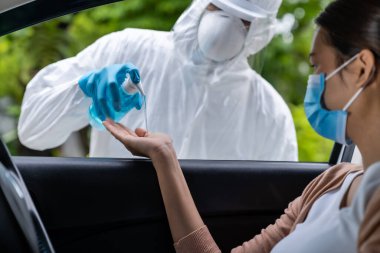 Hastane personeli Coronavirus covid-19 testinden önce Asyalı kadınlara alkol jeli dezenfektanı veriyor. Yeni normal sağlık hizmeti ve tıbbi konsept yoluyla.