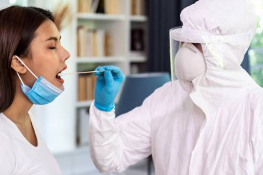 Medical staff with PPE suit test coronavirus covid-19 to asian woman by throat swab at home. New normal health care service at home and medical delivery and COVID-19 testing concept. clipart