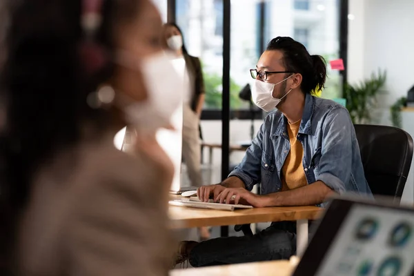 社会的距離の練習で新しい通常のオフィスで働く保護顔マスクを持つアジアオフィスの従業員は 前景にアフリカの同僚にコロナウイルスCovid 19が広がるのを防ぐ — ストック写真