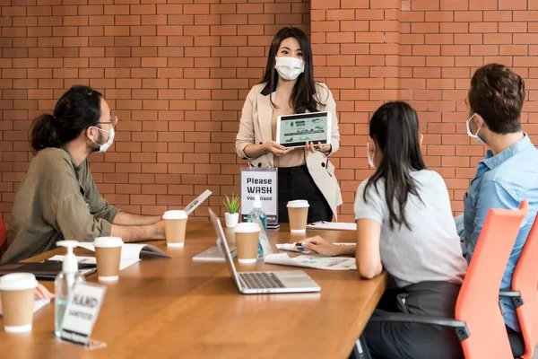 アジアのビジネス女性はブレインストーミングのために彼女の仕事を提示する 彼らは 新しい通常のオフィスで保護面マスクを着用し コロナウイルスCovid 19の拡散を防ぎます — ストック写真