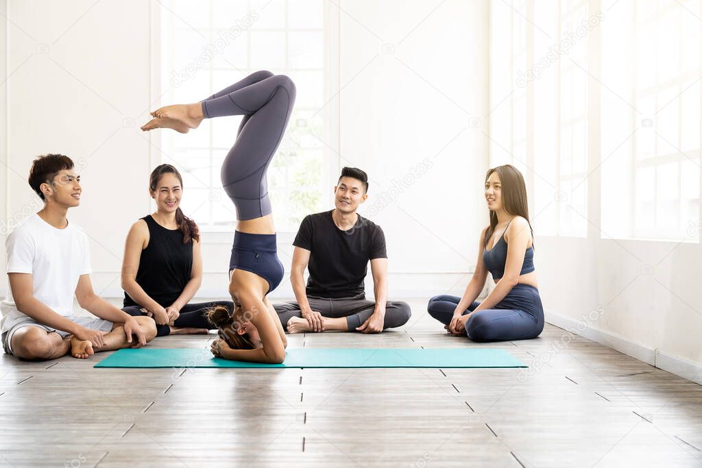 Asian yoga female coach or instructor wear sportswear bra pants show student in fitness studio class  poseture of headstand pose. Yoga Practice Work out exercise and healthy lifestyle concept.