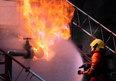 Su sisi tipi yangın söndürücü kullanan itfaiyeci petrol boru hattı sızıntısı ve petrol platformu ve doğalgaz istasyonundaki patlamayla savaşmak için. İtfaiyeci ve endüstriyel güvenlik kavramı.